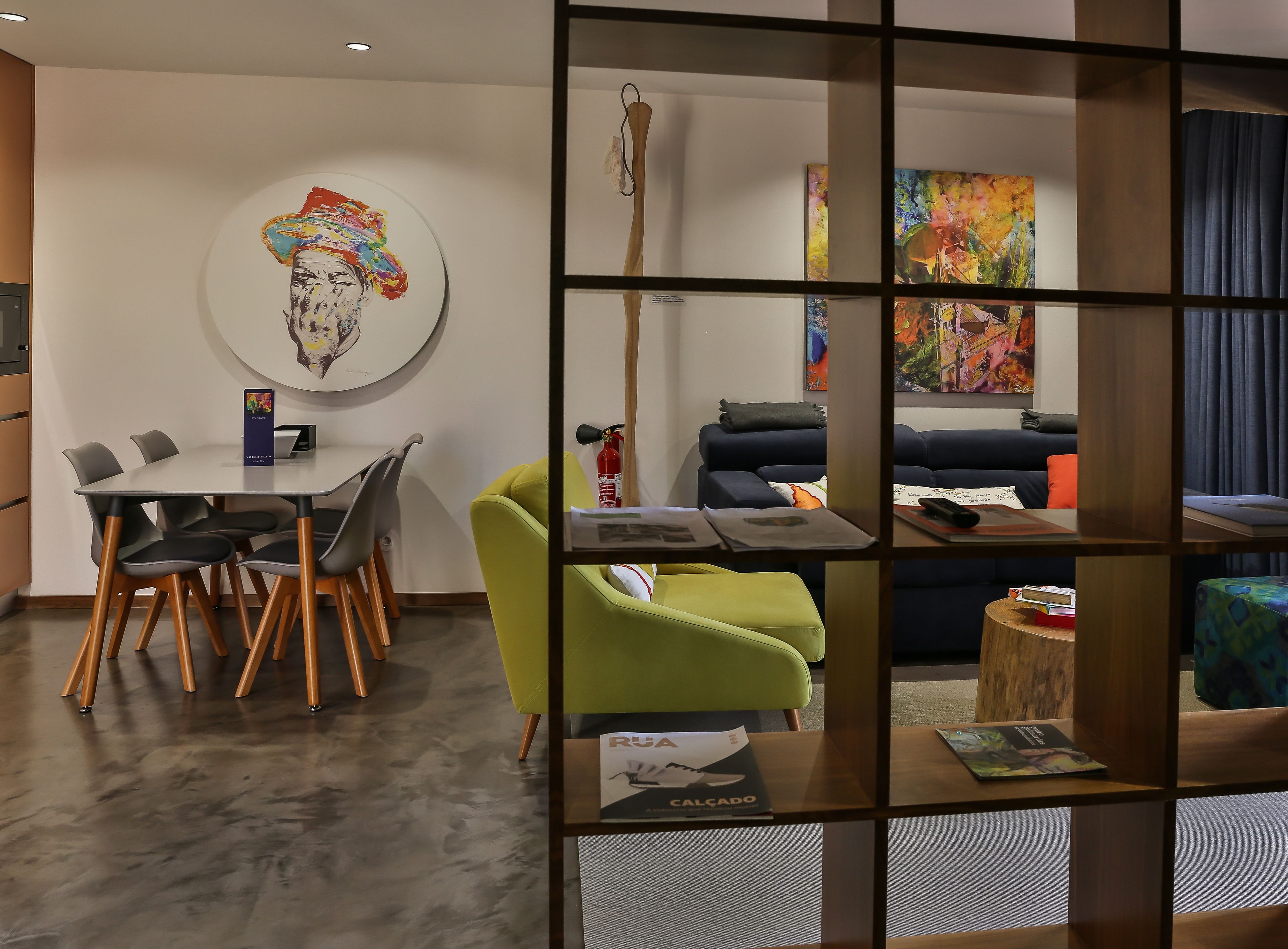 A modern living room with a dining area, a sofa, and a coffee table with books and a remote control.