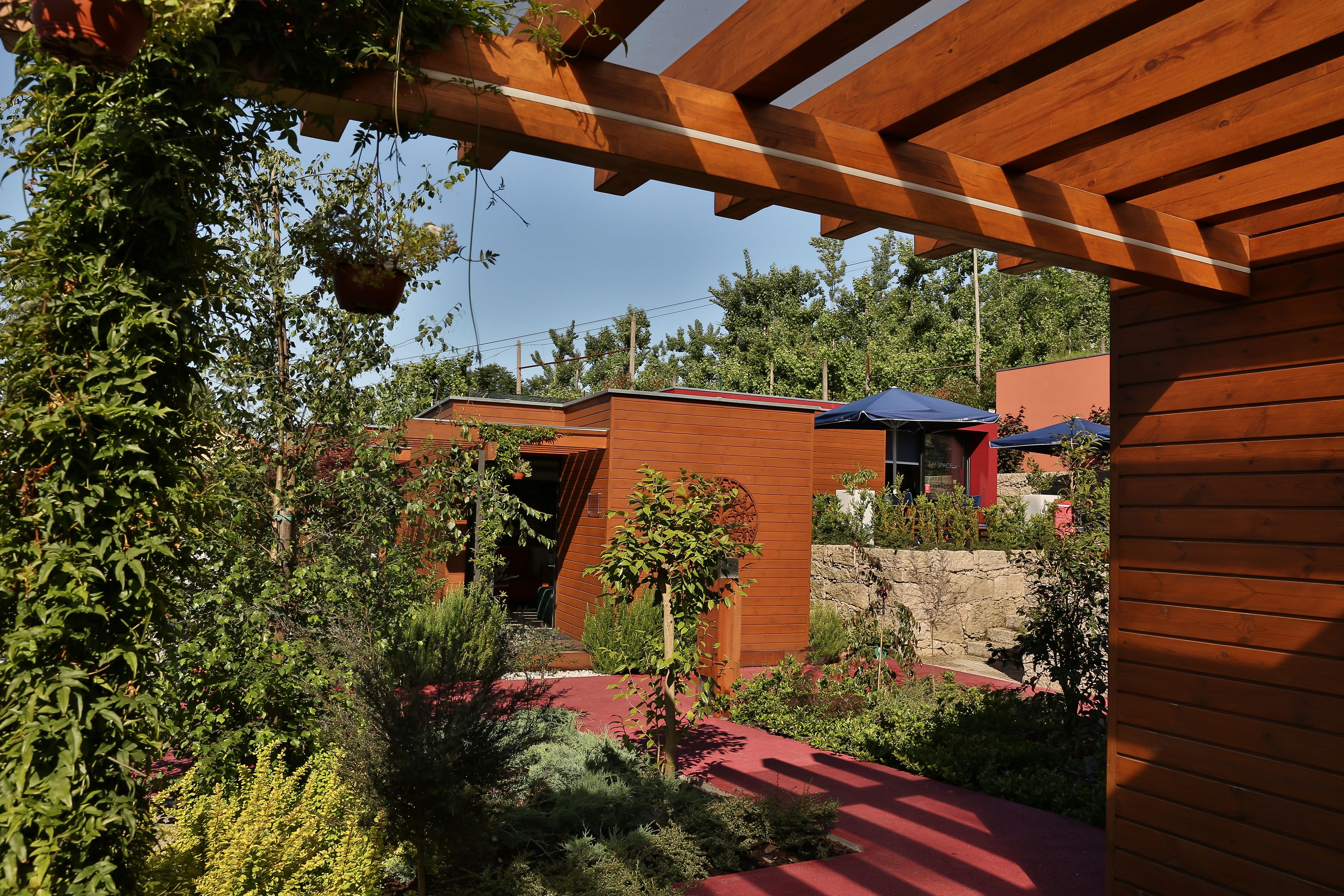 A modern house with a wooden exterior, a stone wall, and a red pathway.