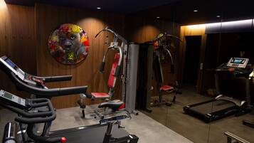 Een fitnessruimte met cardioapparatuur, krachttrainingsmachines en een vastgezet hometrainer.
