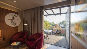 Un interior moderno con dos sillones de terciopelo rojo, una mesa redonda y un amplio ventanal con vistas al exterior.