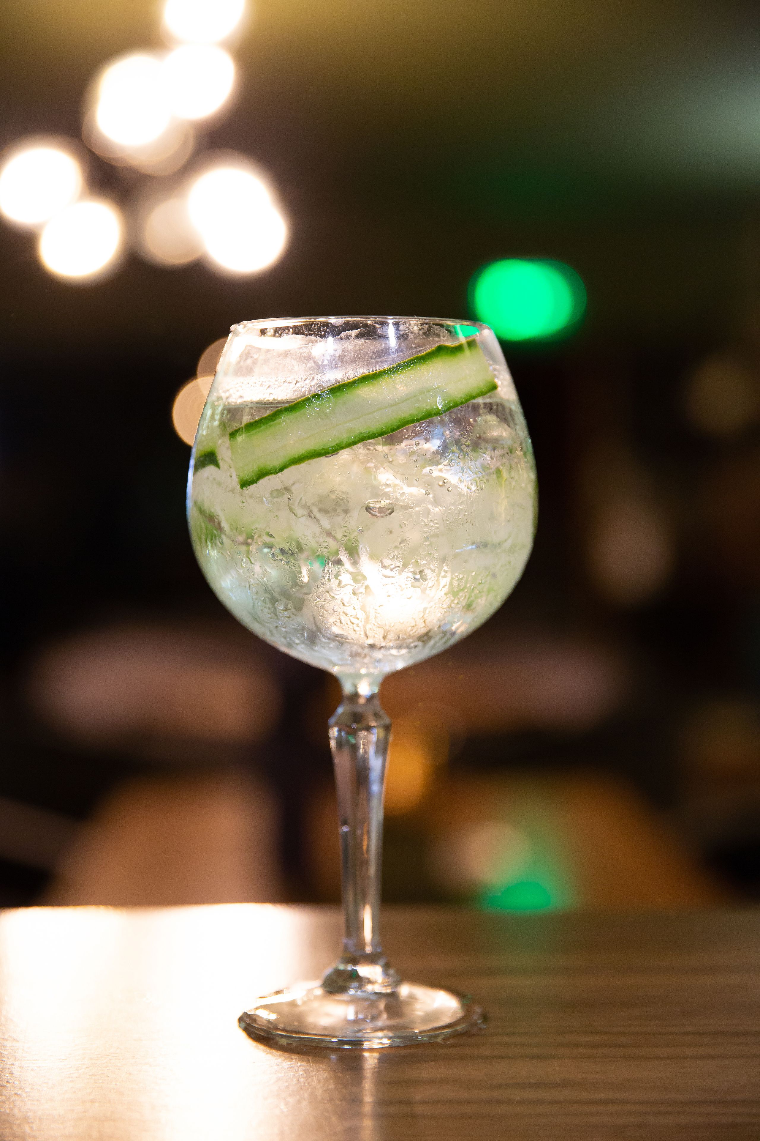 A glass with a lime slice and ice on a wooden surface.