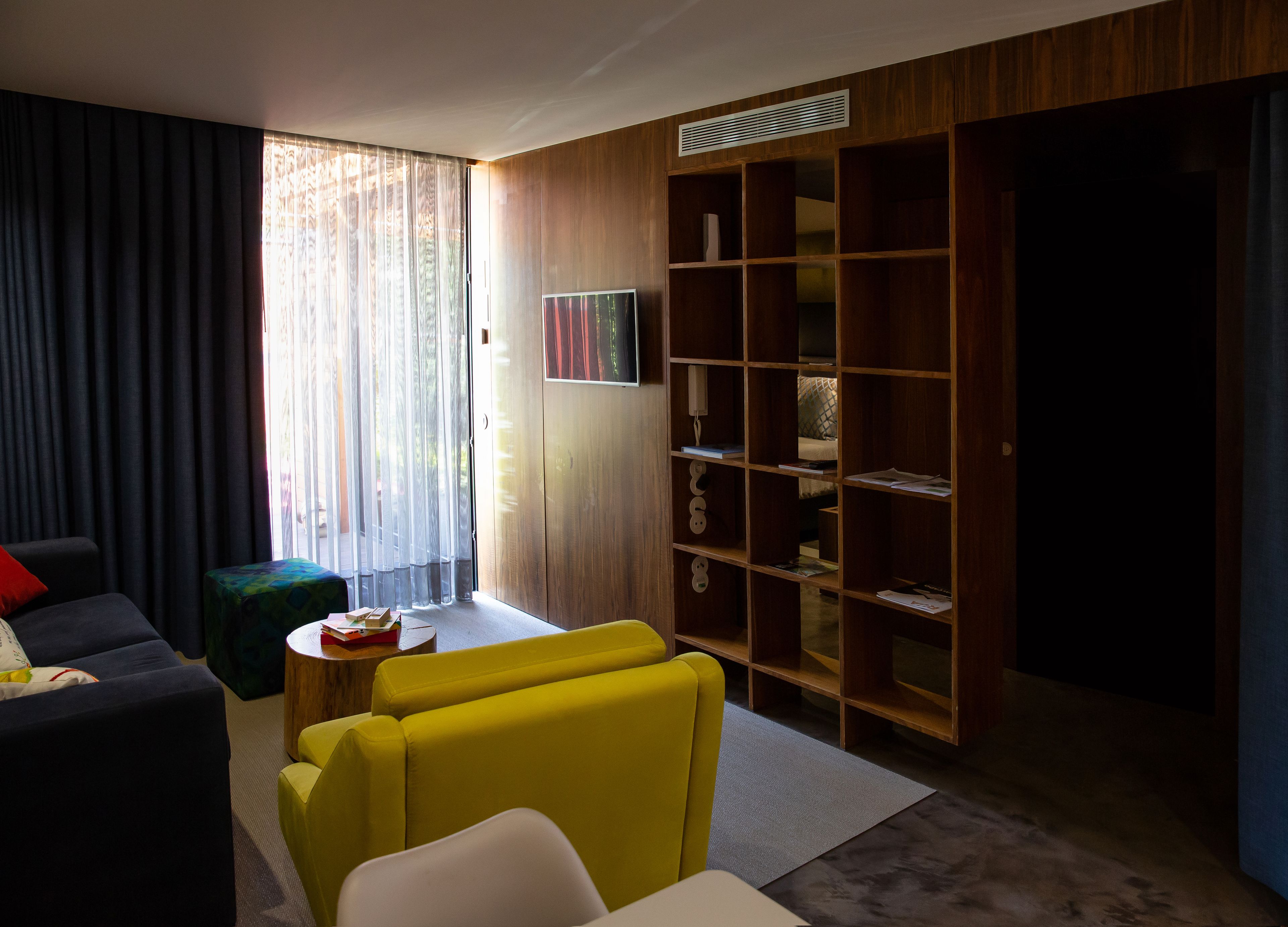 A modern living room with a sofa, yellow armchairs, a coffee table, and a wooden bookshelf.