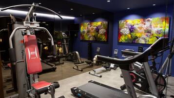 A gym with exercise equipment, a treadmill, and two abstract paintings on the wall.