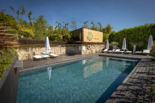 Una piscina cristalina con sillas de descanso y sombrillas, rodeada de vegetación y un edificio que dice 'Happy Place'.