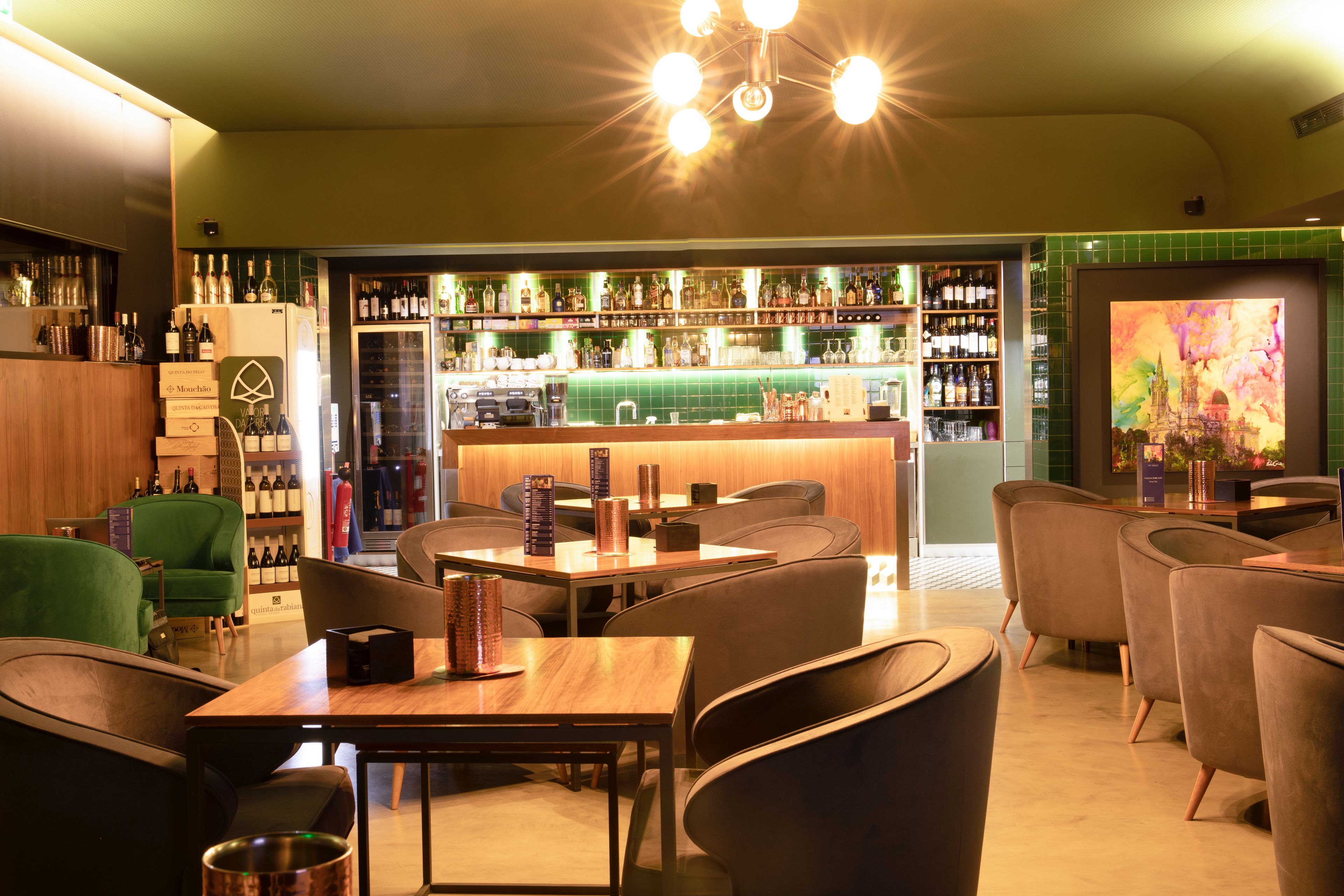 A bar area with seating and a variety of bottles and glasses on shelves.