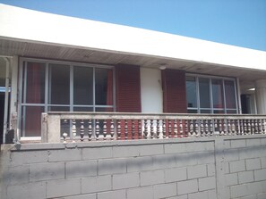A building with a balcony, large windows, and a brick wall. - Shirahono Yado Aoiumi (Ishigaki)