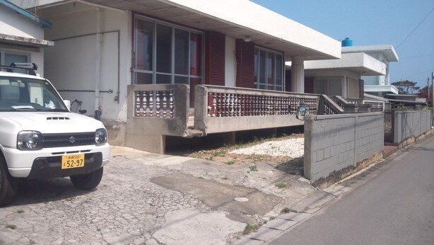 Een woongebouw met een plat dak, grote ramen en een betonnen balkon met sierhekwerk.