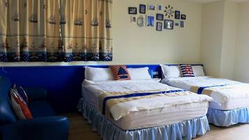 Ein Zimmer mit zwei Betten, einem blauen Sessel und einem Vorhang mit Meeresmotiven.