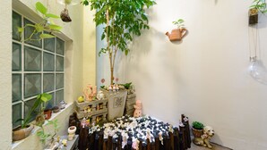 A small, cozy room with a large window, a potted tree, and various decorative items including figurines and plants. - Puli Waltz Villa (Puli)
