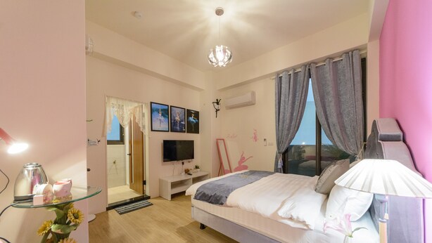 A modern bedroom with a bed, a vanity with a mirror, a television, and a window with curtains. - Puli Waltz Villa (Puli)