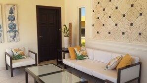 A living room with a sofa, two armchairs, a coffee table, and a door. - Sosua villa tropical retreat with ocean views (Sosúa)