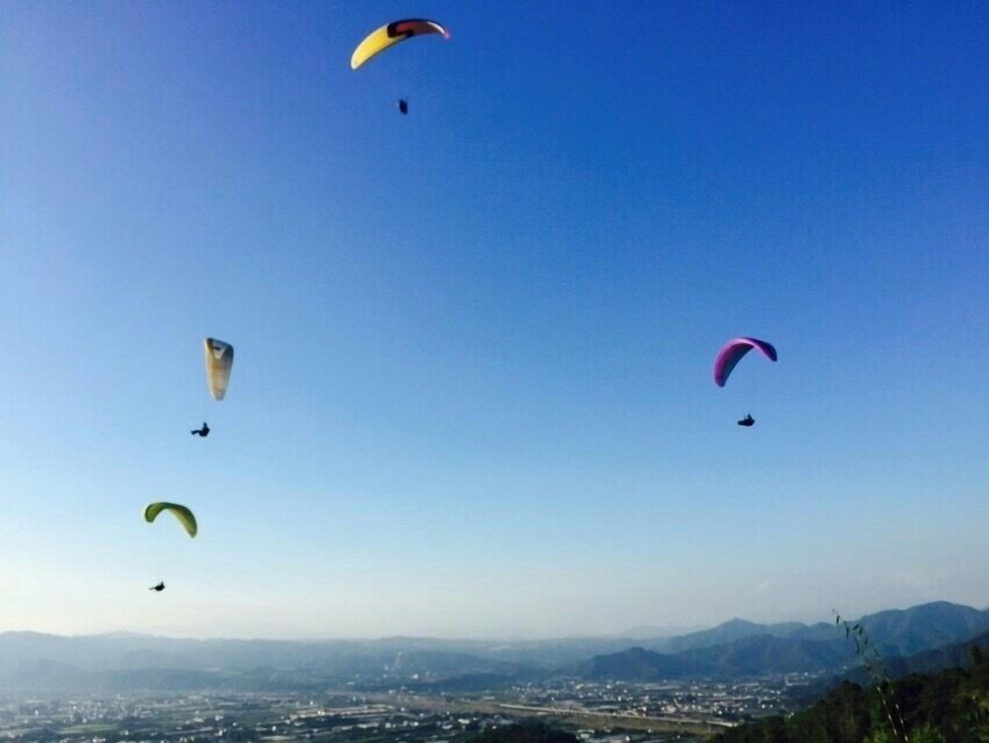 A clear sky with multiple parachutes in various colors.