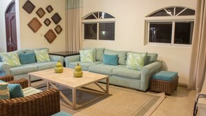 A living room with a light blue sofa set, two green patterned throw pillows, a wooden coffee table, and a woven basket. - Touch of elegance! 6 Bedroom near the beach (Sosúa)