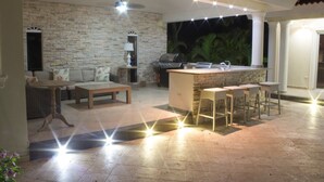 An outdoor living area with a stone wall, a sofa, a coffee table, and a bar with stools. - Touch of elegance! 6 Bedroom near the beach (Sosúa)