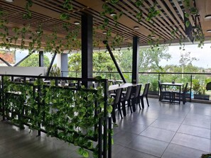 An indoor dining area with tables and chairs, a ceiling with hanging plants, and large windows allowing natural light. - Hotel Brisas de Calima (Cali)