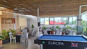 Een pooltafel met 'EUROPA'-branding, een zithoek met stoelen en tafels, en potplanten.