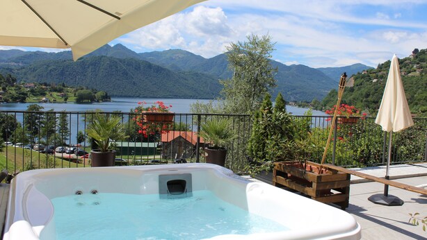 Un bain à remous sur un balcon donnant sur un lac, avec des montagnes en arrière-plan.