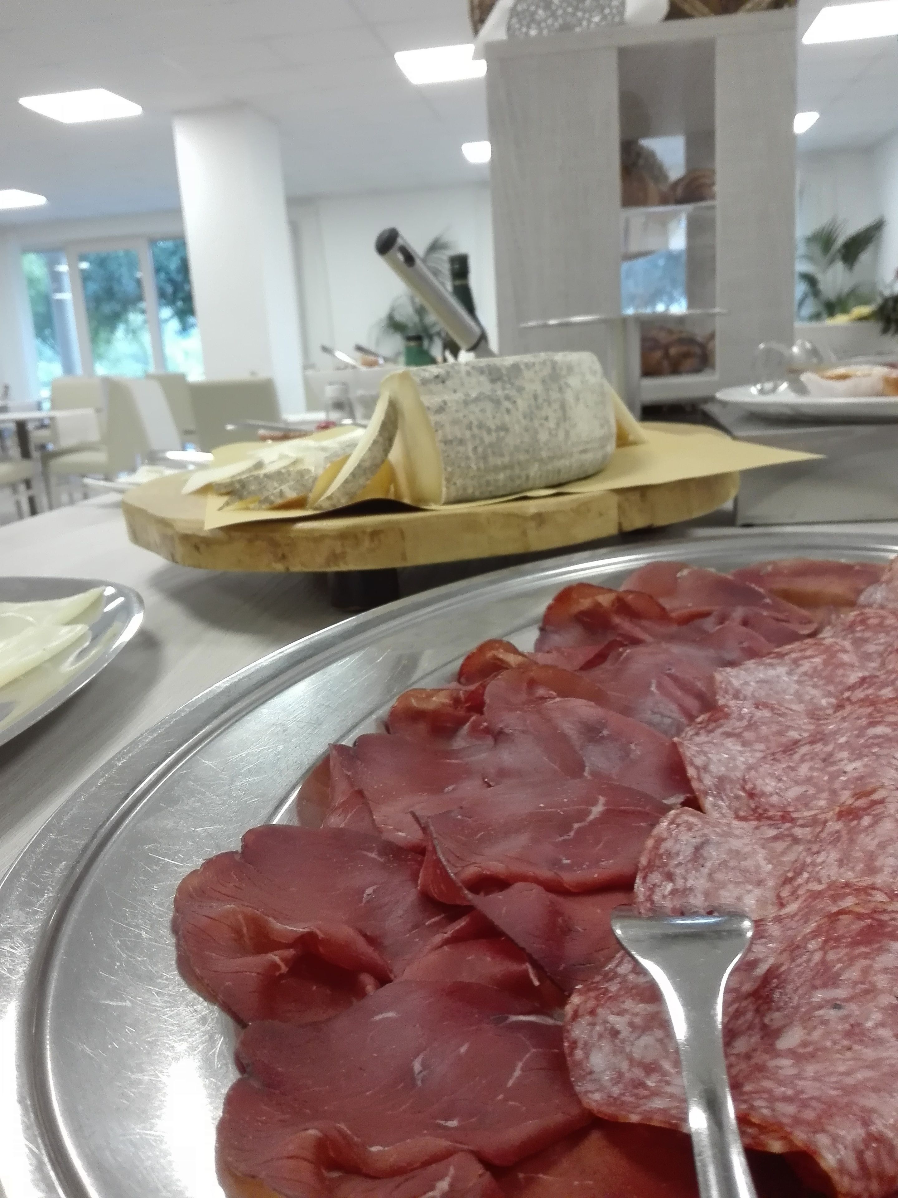 Un comedor con un plato de embutidos y un queso redondo sobre una tabla de madera.