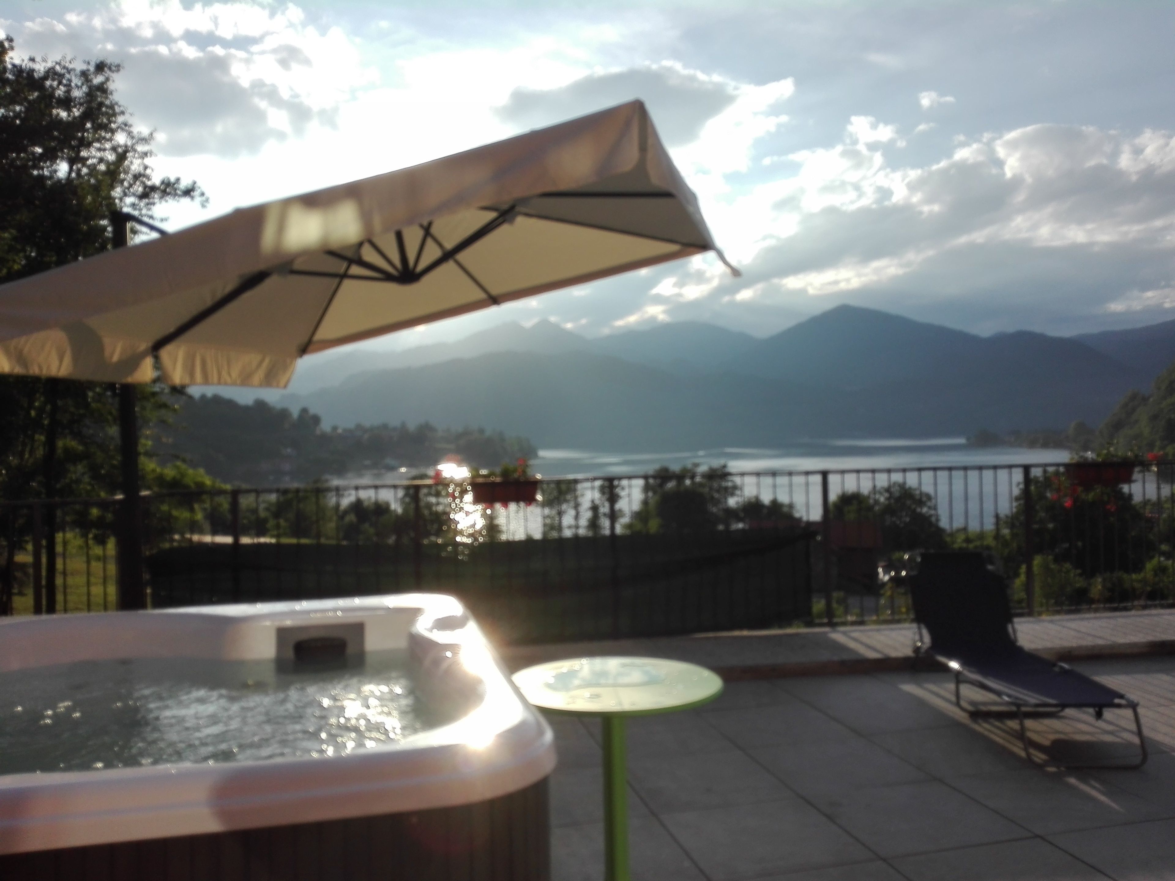 Un bain à remous, un espace salon extérieur et une vue sur un lac avec des montagnes en arrière-plan.