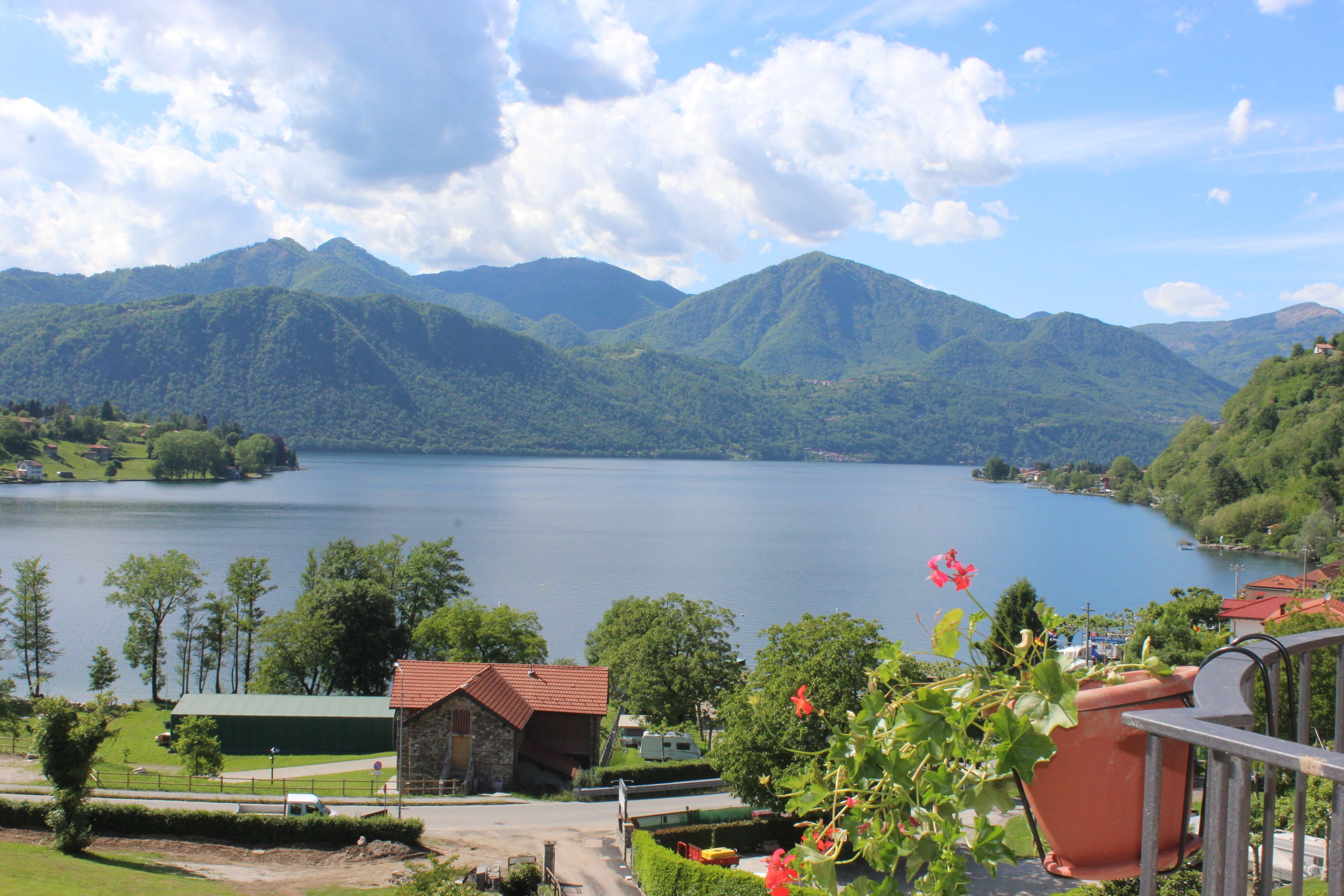 A lakeside property with a stone building, a paved driveway, and a view of the lake and mountains.