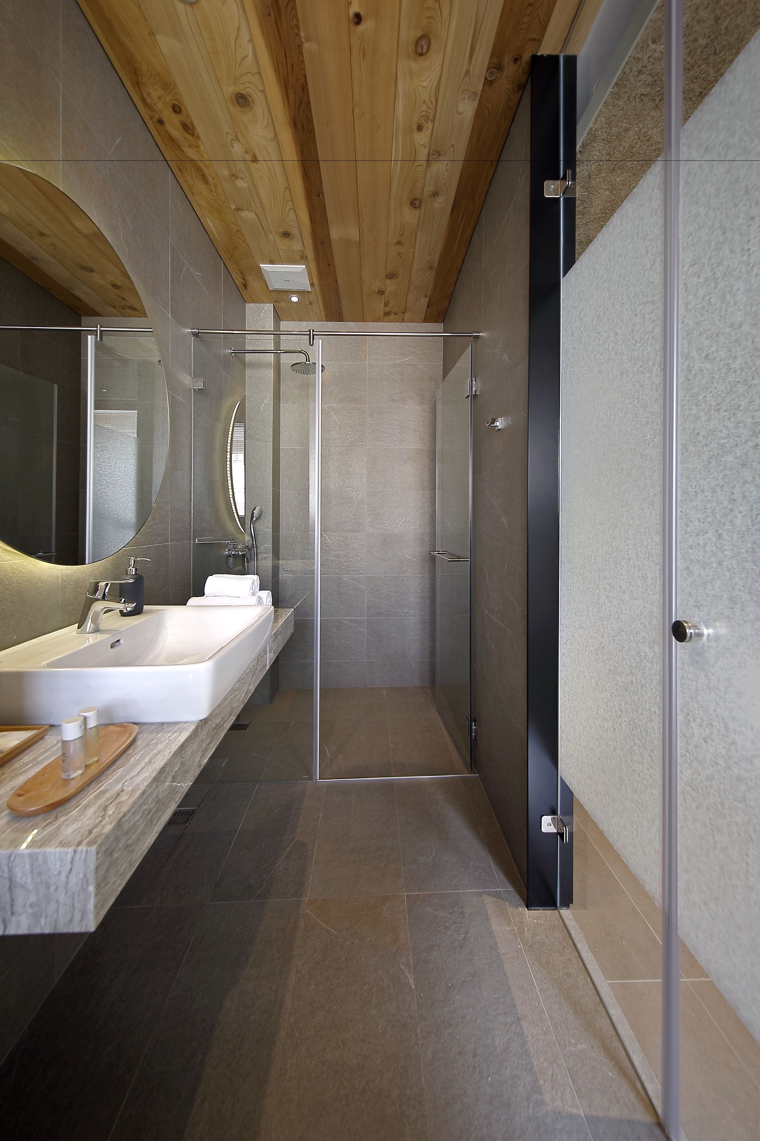 A modern bathroom with a large sink, a mirror, and a shower area.