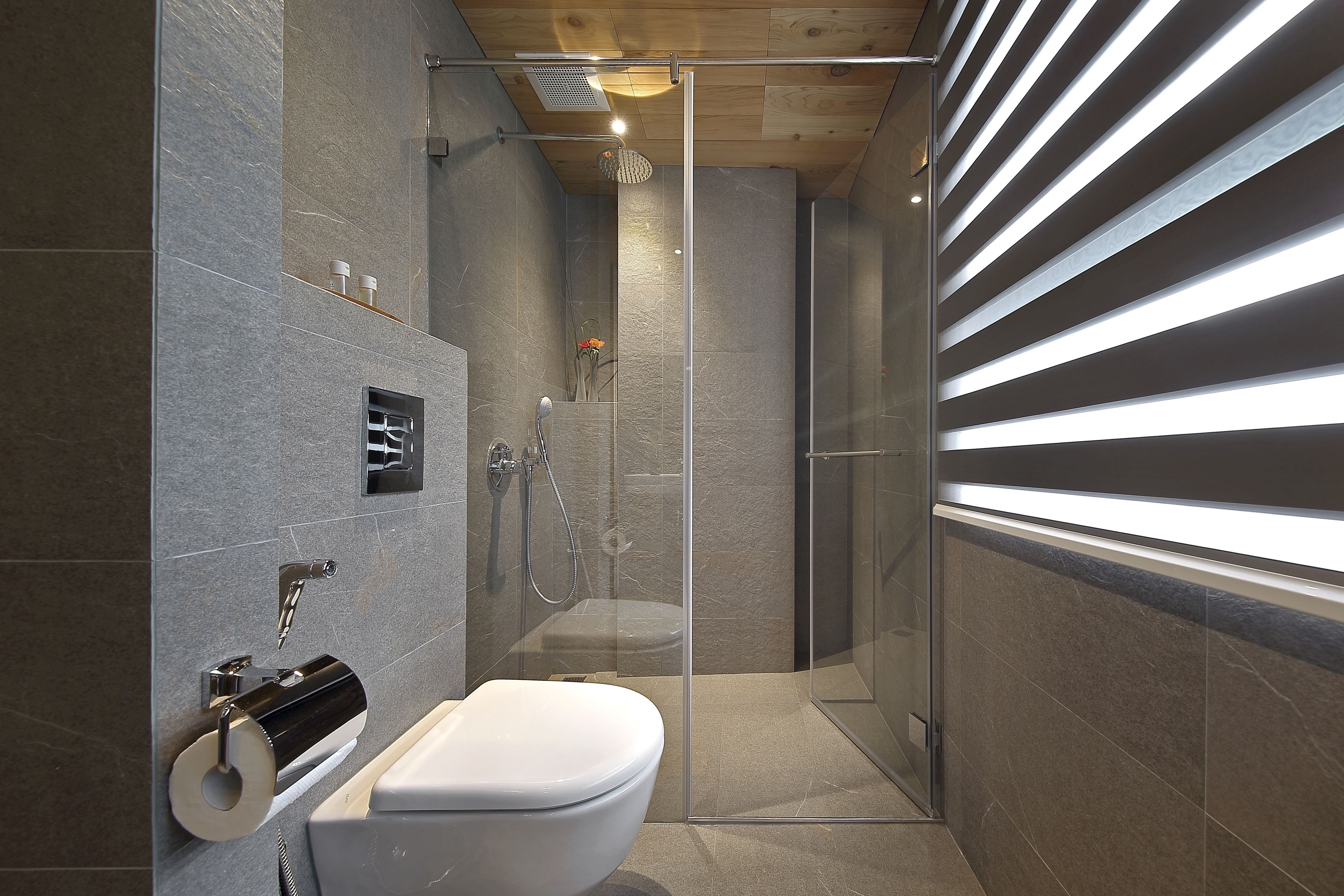 Une salle de bain moderne avec une douche à parois de verre, des toilettes et un porte-serviettes.