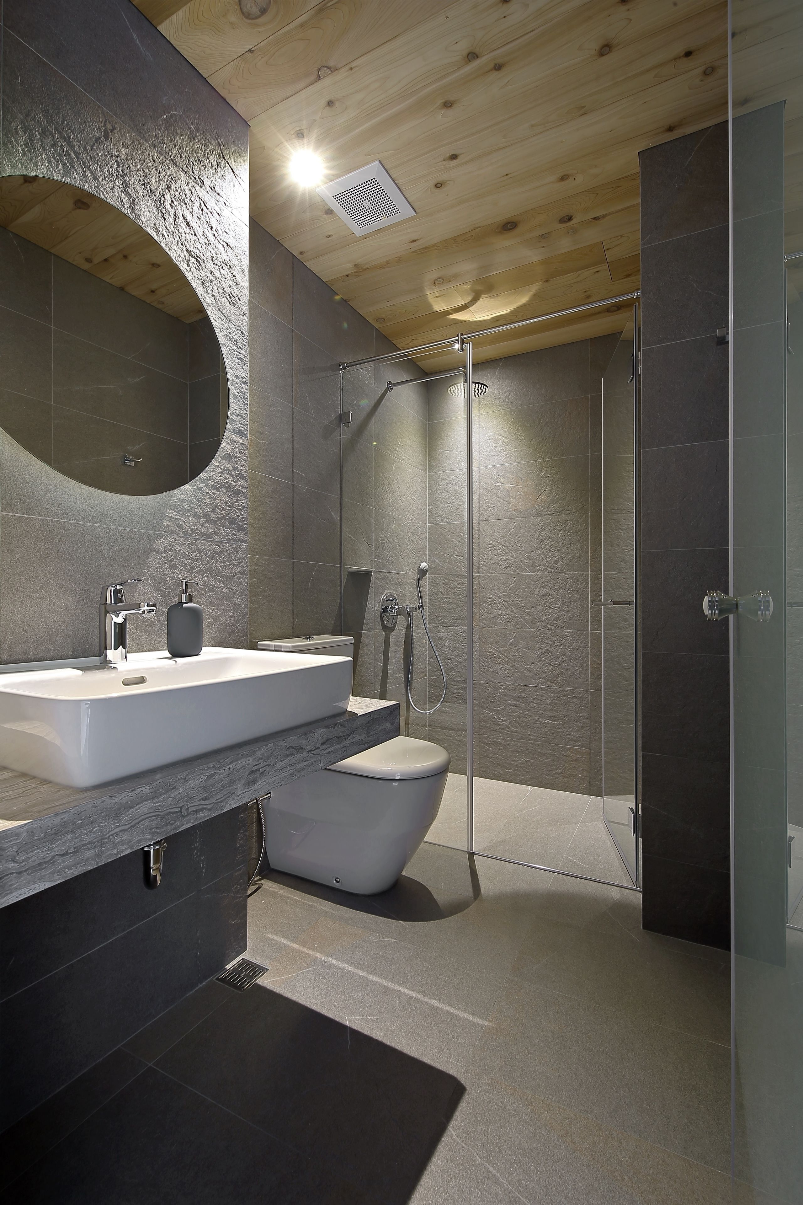 A modern bathroom with a large sink, mirror, and shower.