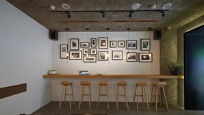 Een receptiegedeelte met een houten balie, barstoelen en ingelijste foto’s aan de muur.