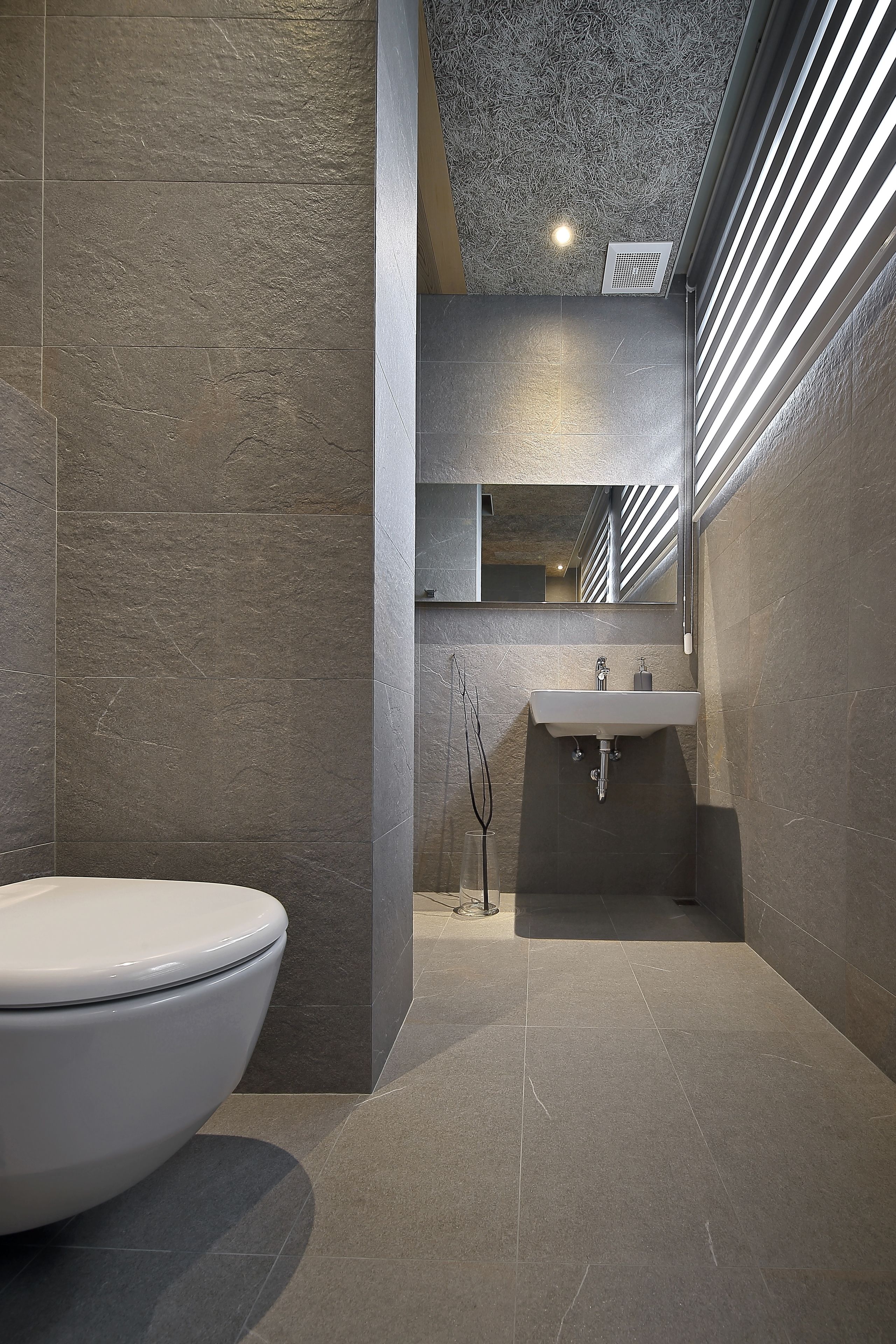 A modern bathroom with a large toilet, a sink, and a mirror.