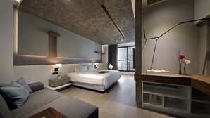 Een moderne hotelkamer met een groot bed, een slaapbank, een bureau en uitzicht op de stad.