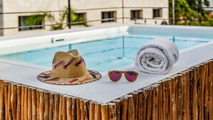 A poolside area with a hat, sunglasses, and a towel on a wooden deck. - Hotel Banana Boutique & Spa by Paradise Hotels - 5th Av Playa del Carmen (Playa del Carmen)