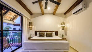 A bedroom with a large bed, wooden ceiling beams, an air conditioning unit, and a view of a building through a glass door. - Hotel Banana Boutique & Spa by Paradise Hotels - 5th Av Playa del Carmen (Playa del Carmen)