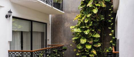 A narrow courtyard with a vertical garden, balconies, and a tiled floor.