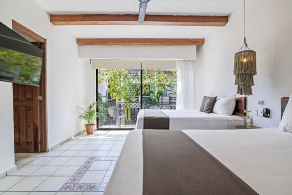 A hotel room with two beds, a TV, a balcony with a view of trees, and a hanging light fixture. - Hotel Banana Boutique & Spa by Paradise Hotels - 5th Av Playa del Carmen (Playa del Carmen)