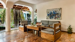 A spacious living area with a wooden coffee table, a sofa, and a chair. There is a painting on the wall and a potted plant on the floor. - Hotel Banana Boutique & Spa by Paradise Hotels - 5th Av Playa del Carmen (Playa del Carmen)