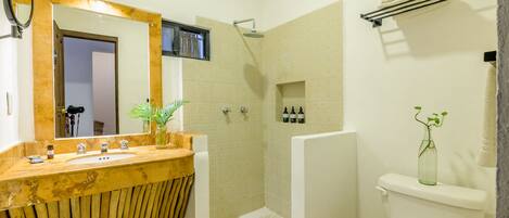 A bathroom with a wooden vanity, a large mirror, a shower, and a toilet.