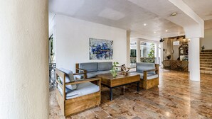 A spacious living area with a modern sofa set, a wooden coffee table, and a large abstract painting on the wall. - Hotel Banana Boutique & Spa by Paradise Hotels - 5th Av Playa del Carmen (Playa del Carmen)