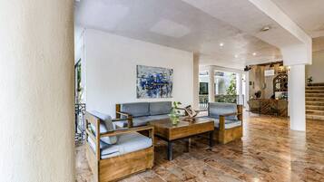 Un espacio habitable amplio con un juego de sofás moderno, una mesa de centro de madera y un cuadro abstracto grande en la pared.