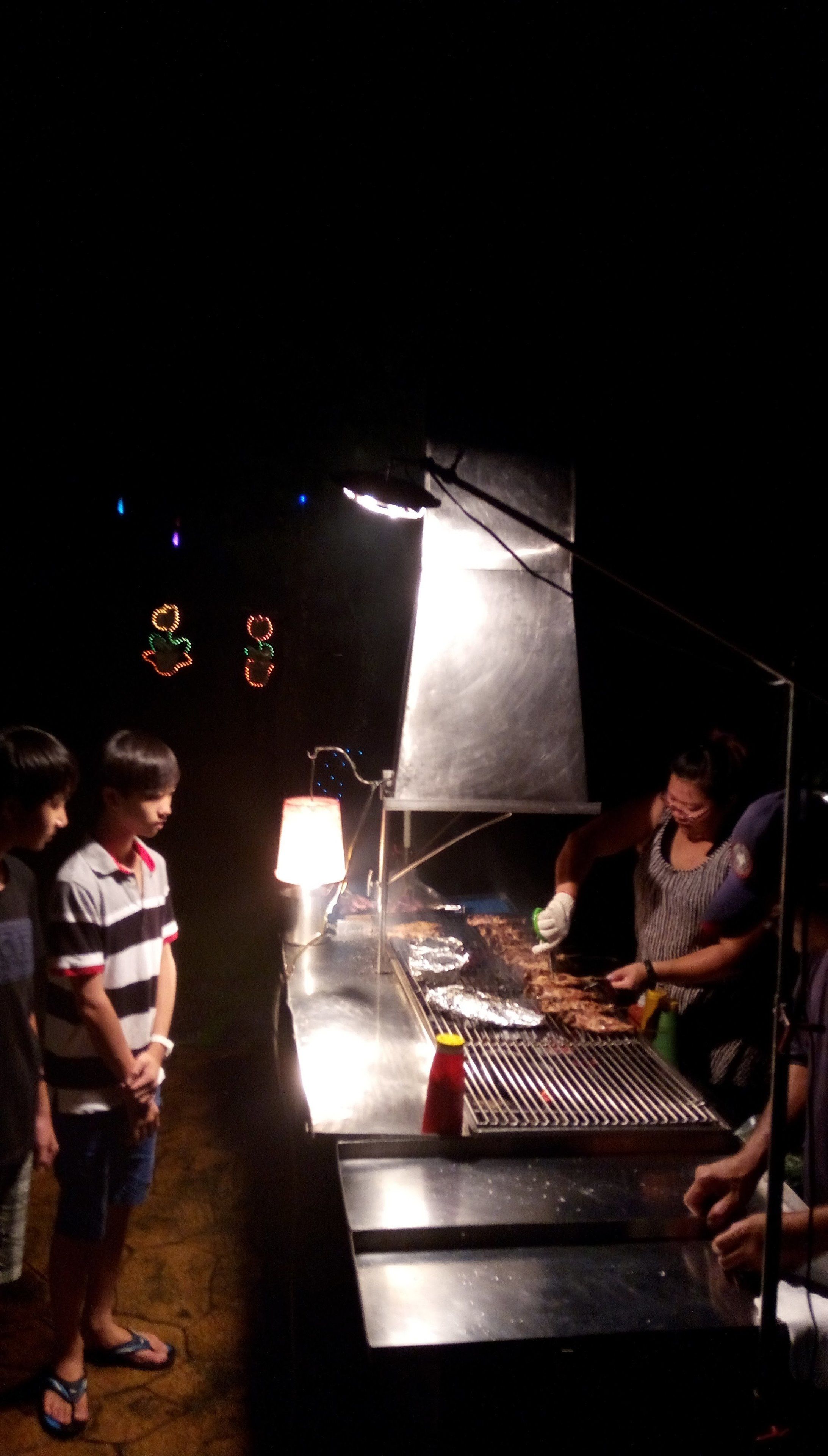 Un grupo de personas alrededor de una parrilla por la noche.