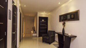 A modern hallway with a black upholstered chair, a console table with a vase, and a framed artwork on the wall.
