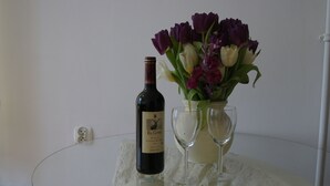 Une bouteille de vin El Corte et deux verres à vin sont posés sur une table en verre, à côté d’un vase de tulipes.