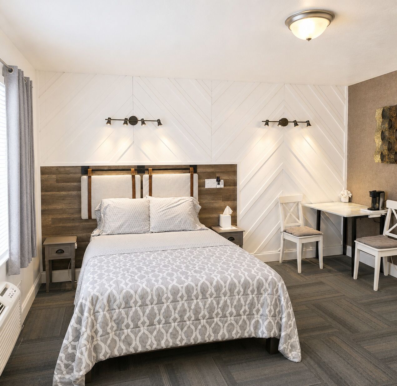 Una habitación de hotel con cama, mesitas de noche, escritorio y una silla.
