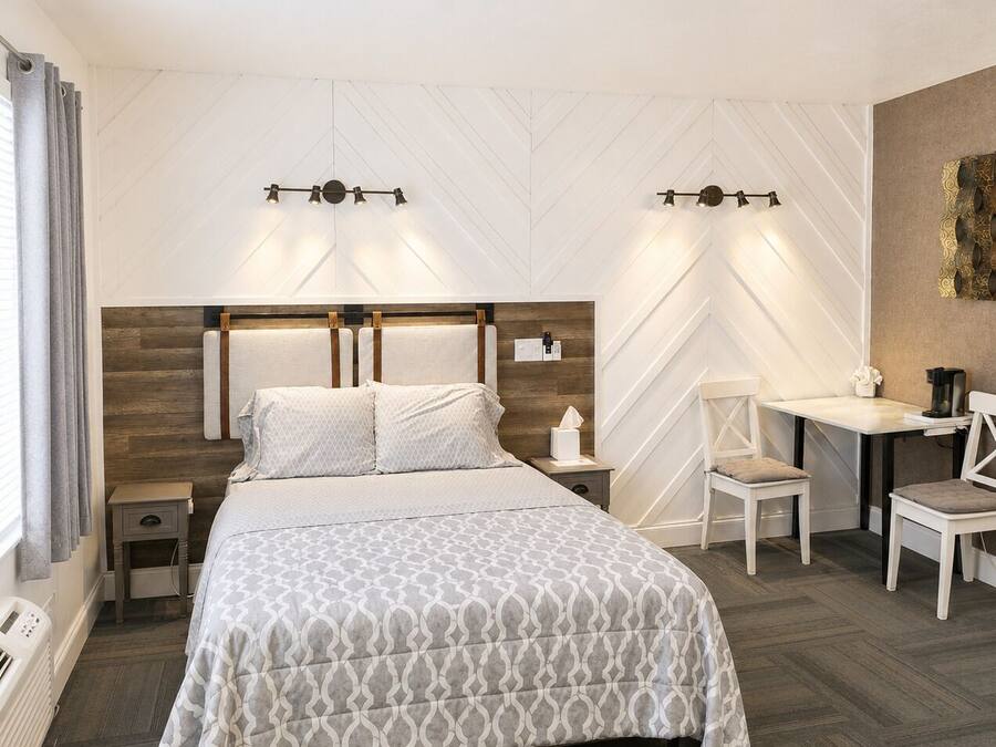 Una habitación de hotel con cama, mesitas de noche, escritorio y una silla.