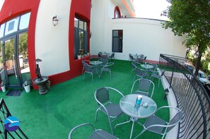 Eine Außenpatio mit grünem Kunstrasen, Metallstühlen und -tischen.