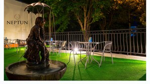 An outdoor seating area with a statue, tables, and chairs.