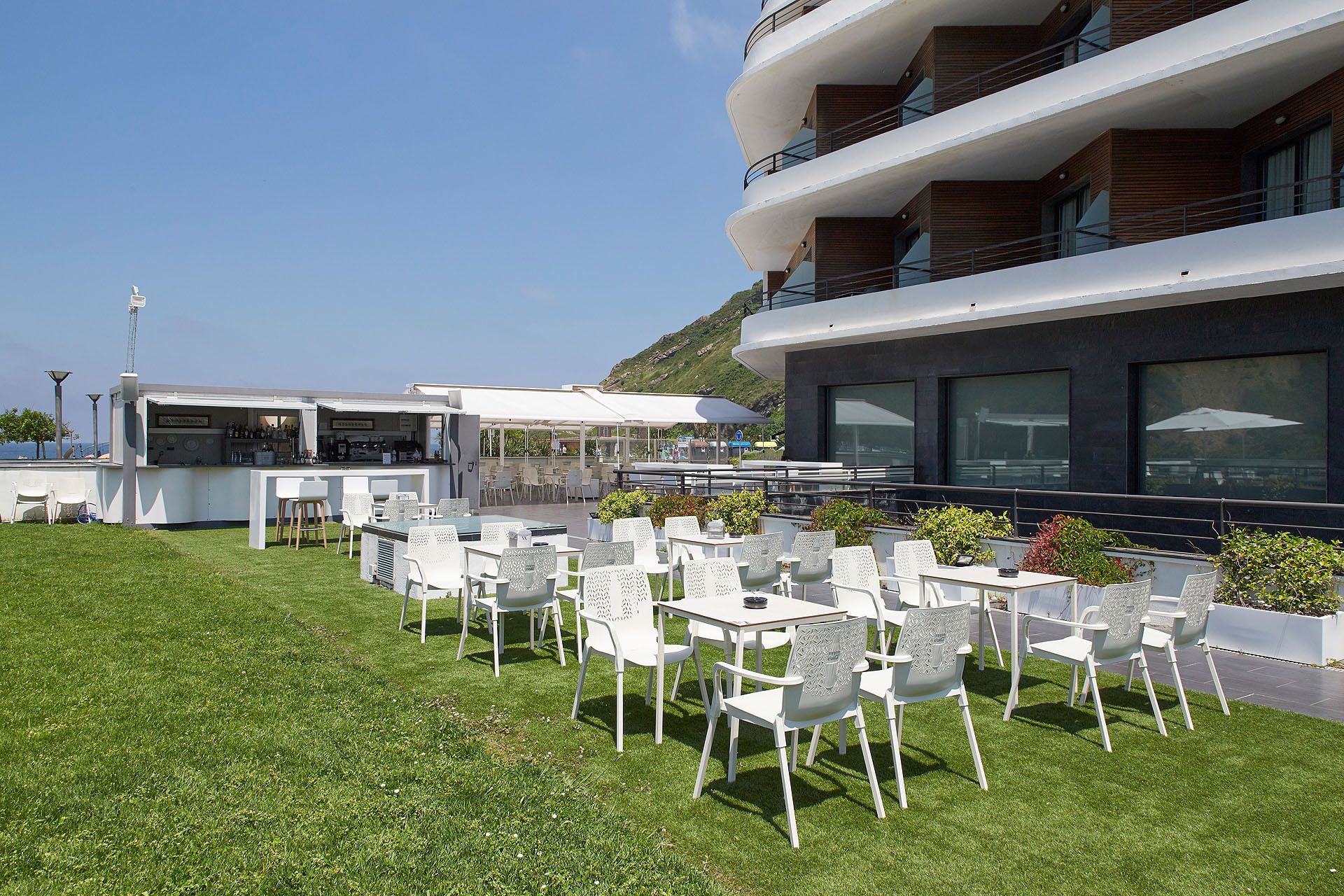 Terraza en la azotea con mobiliario exterior y una zona de bar, con vistas a un paisaje pintoresco.