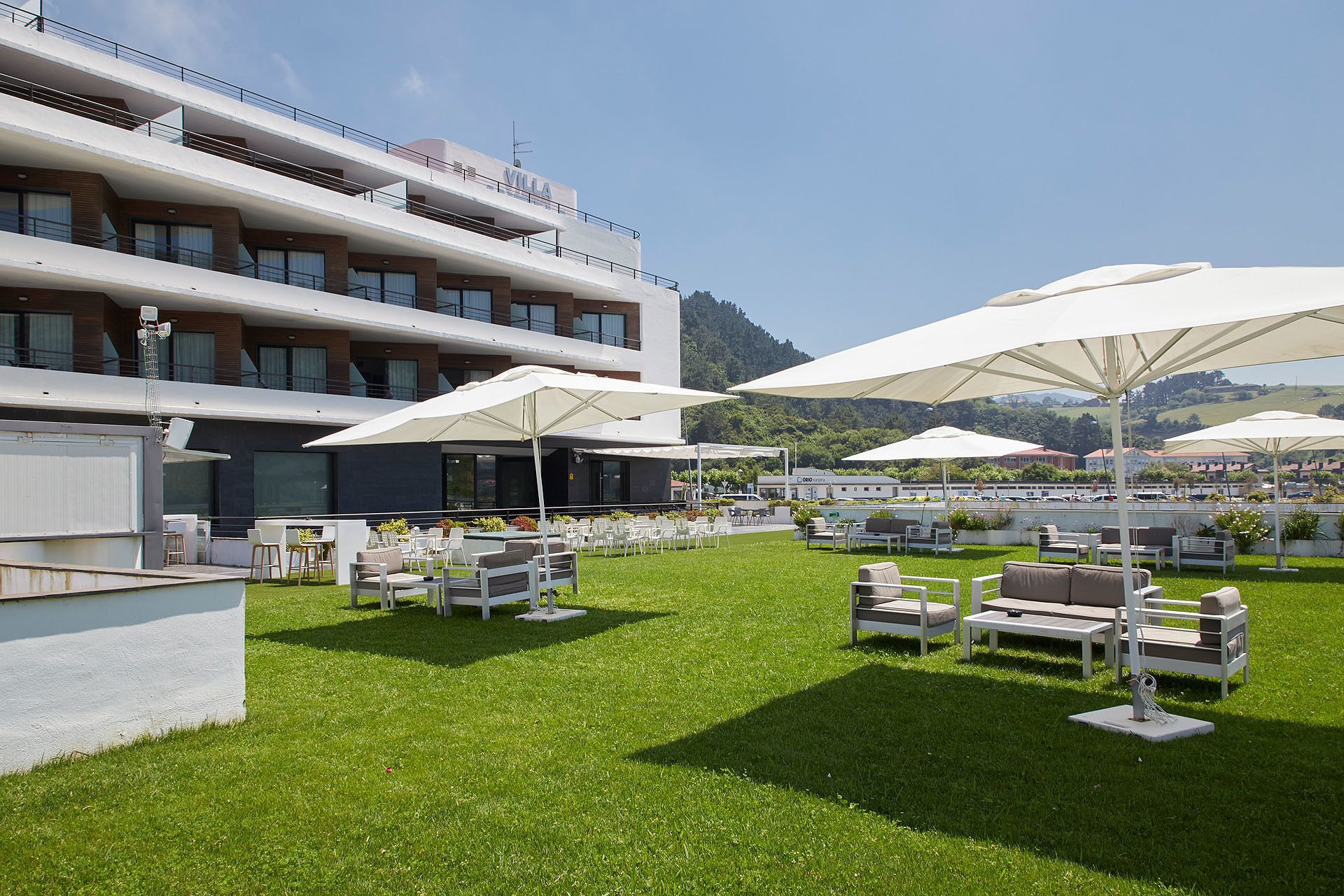 Ein Hotel mit Außenbereich, Sonnenschirmen, einem Pool und Blick auf die umliegende Landschaft.