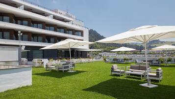 Ein Hotel mit Außenbereich, Sonnenschirmen, einem Pool und Blick auf die umliegende Landschaft.