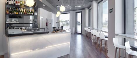 Uma área de bar moderna com uma ilha central, banquetas e um display de vinhos.