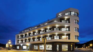 Et hotel med flere etager, altaner, store vinduer og en veloplyst facade.